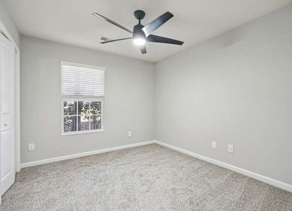 A room with a ceiling fan and a window with blinds.