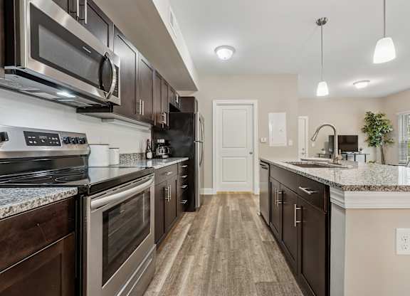 A kitchen with dark wood cabinets and stainless steel appliances.