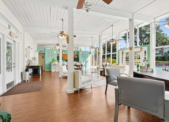 A white chair is in the middle of a room with a wooden floor.