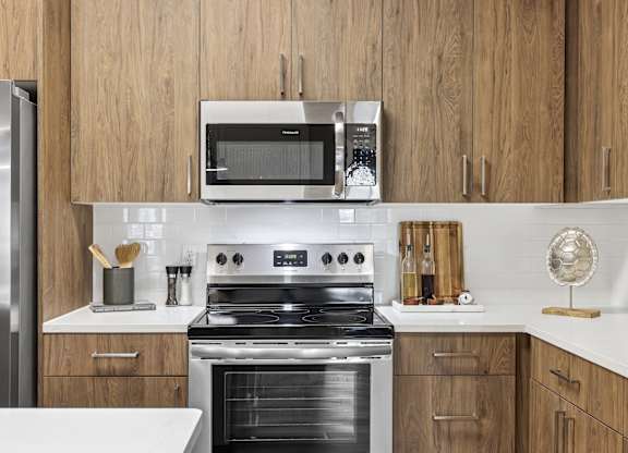 A modern kitchen with a stainless steel refrigerator, a microwave, and a stove top oven.at The Exchange at Crestview Apartments, Crestview, FL, 32536
