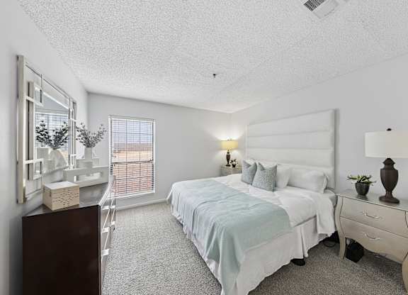A bedroom with a bed, nightstand, and a window with blinds.