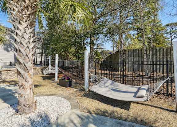 A hammock is strung between two poles in a yard.