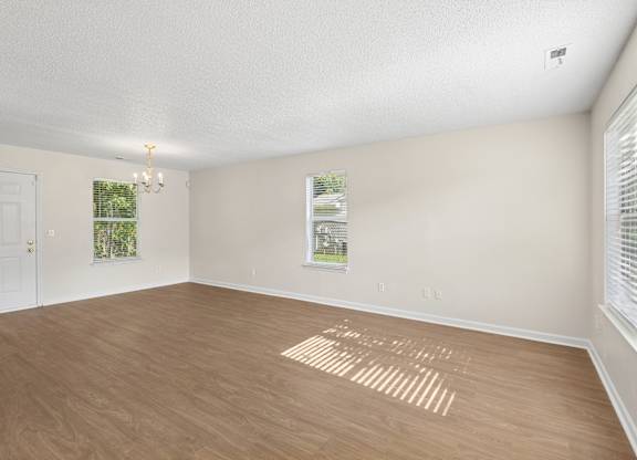 A room with wooden flooring and a window with blinds.