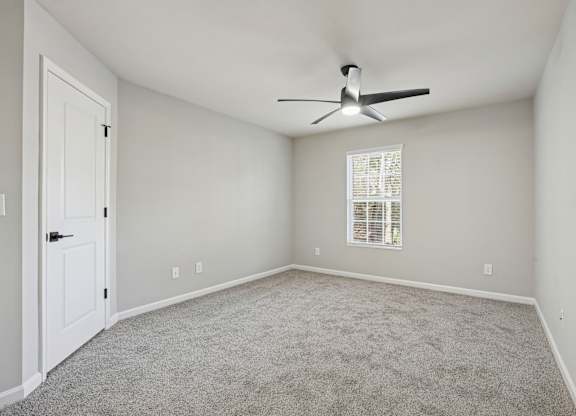 A room with a ceiling fan and a window with blinds.