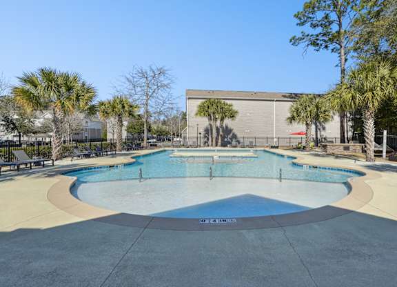 A large outdoor swimming pool surrounded by palm trees.