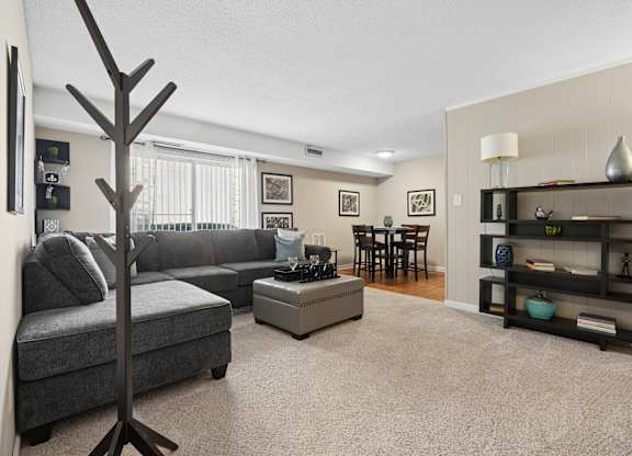 A living room with a grey couch, a tree-shaped object, and a shelf with various decorative items.