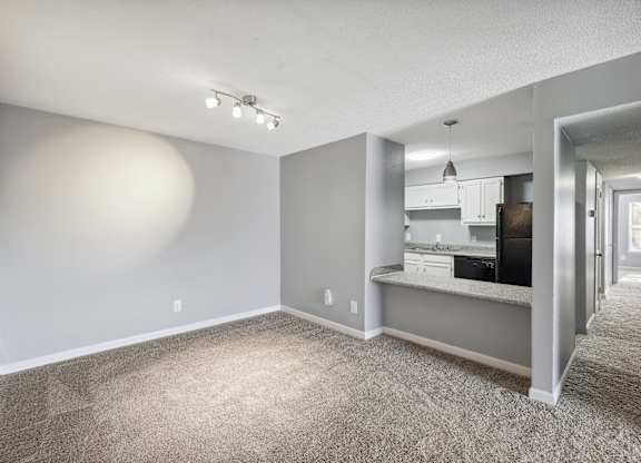 the living room and kitchen of an apartment with gray walls and carpet  at Governors House, Huntsville