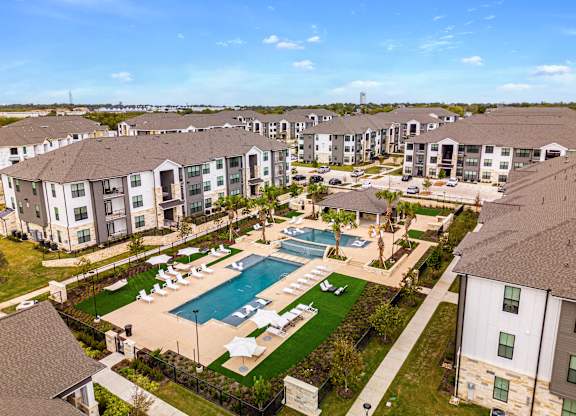an aerial view of the resort style pool with lounge chairs and umbrellas at The Parker Austin, Pflugerville, Texas