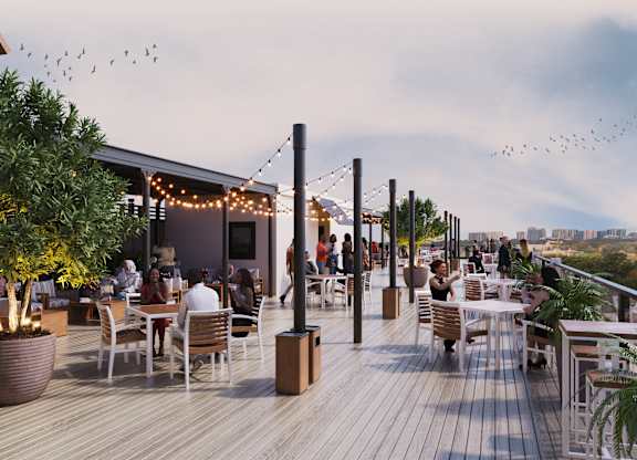 A group of people are sitting at tables on a wooden deck.