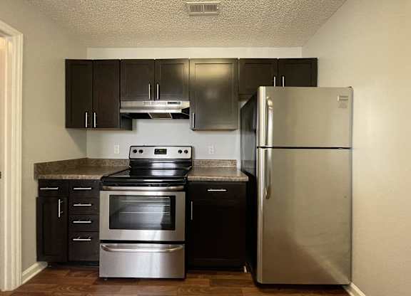 Kitchen with stainless steel appliances and black cabinets at The Chase, Burlington, 27215