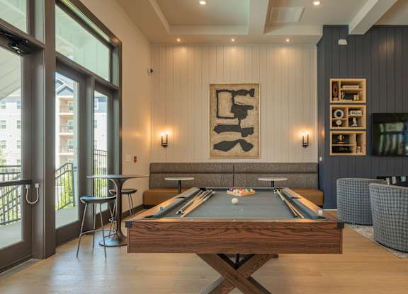 A pool table is in the middle of a room with a fireplace and a TV at The Ashton at East Park Apartments, Georgia, 30144
