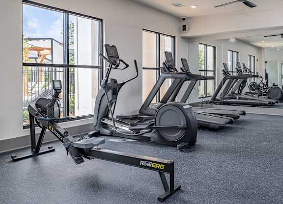 A gym with a variety of equipment including treadmills and elliptical machines at The Collective Upper Westside Apartments, Atlanta
