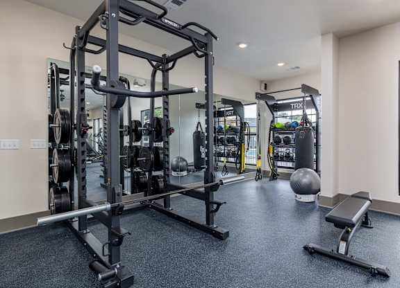 A gym with a variety of equipment including a squat rack, bench, and weights at The Collective Upper Westside Apartments, Atlanta, 30318