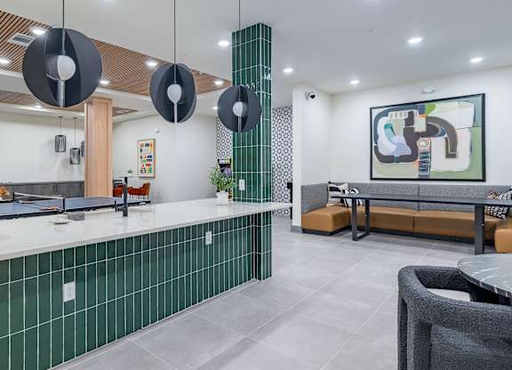 A modern kitchen with green tiled backsplash and a grey countertop at The Collective Upper Westside Apartments, Atlanta