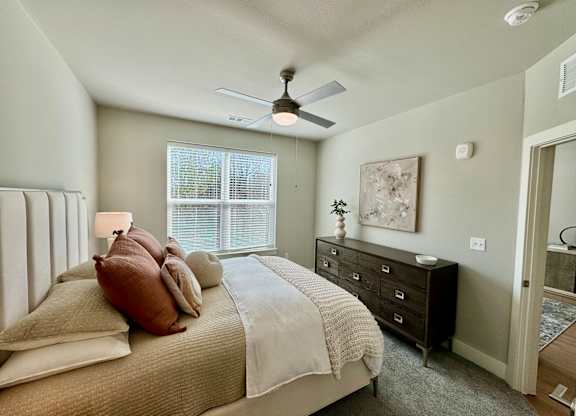 A bedroom with a bed, dresser, and ceiling fan at The Collective Upper Westside Apartments, Georgia