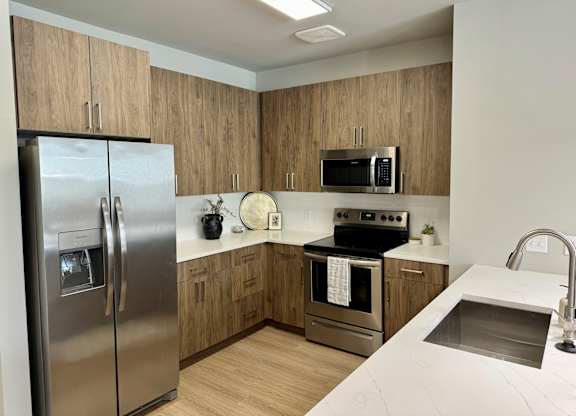 A kitchen with a stainless steel refrigerator, microwave, oven, and sink at The Collective Upper Westside Apartments, Atlanta, 30318