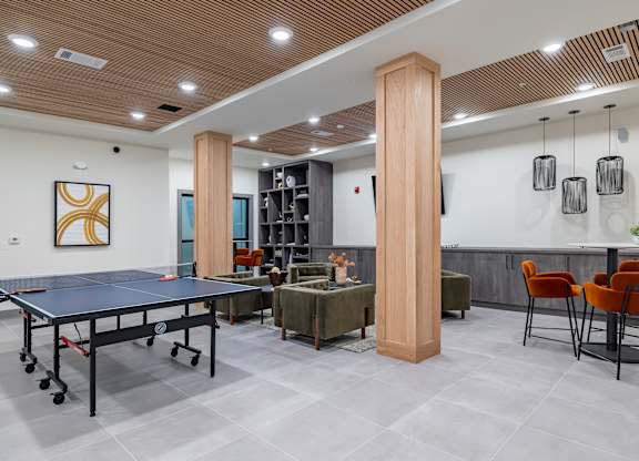 A room with a ping pong table, chairs, and a bookshelf at The Collective Upper Westside Apartments, Georgia, 30318