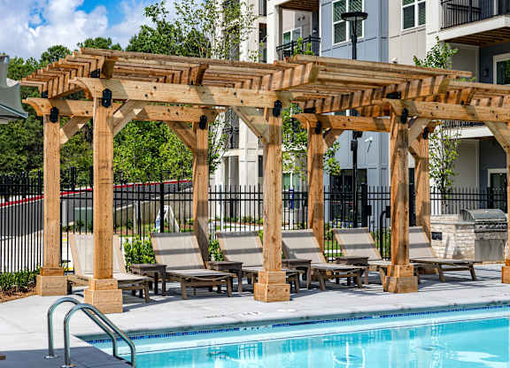 A wooden pergola over a pool with lounge chairs underneath at The Collective Upper Westside Apartments, Atlanta, Georgia