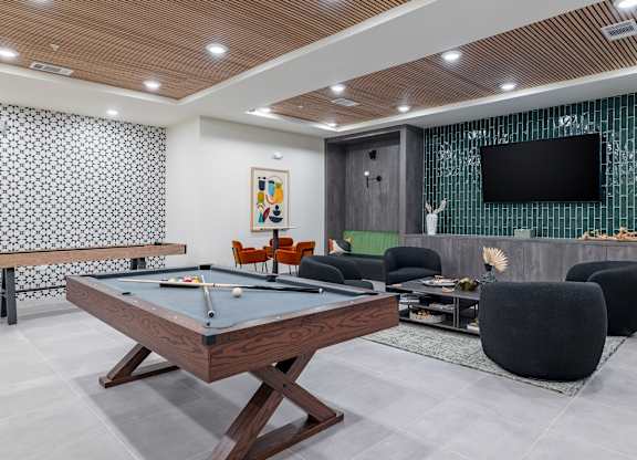 A billiard table is in the middle of a room with a television and a pool table at The Collective Upper Westside Apartments, Atlanta, GA