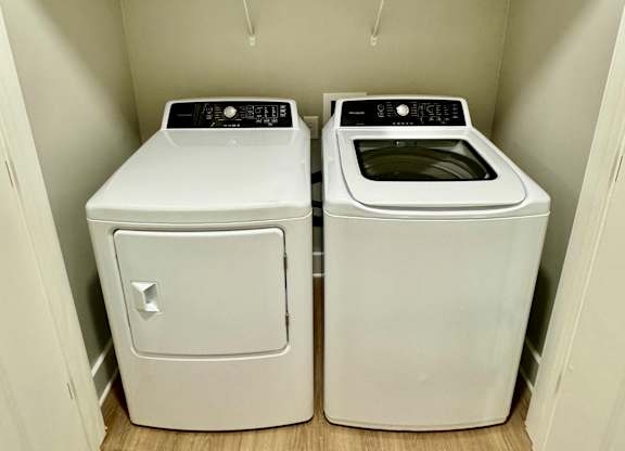 Two white front loading washing machines in a laundry room at The Collective Upper Westside Apartments, Georgia, 30318