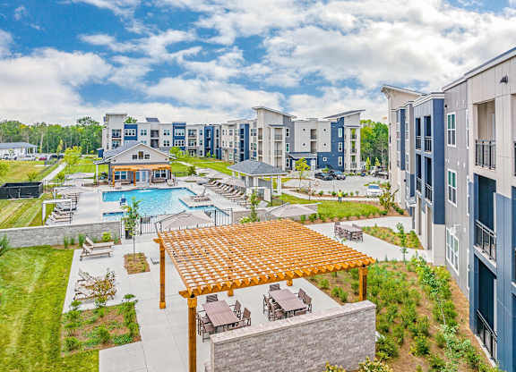 A large outdoor swimming pool surrounded by a wooden deck and lounge chairs at The Percy Apartments, Tennessee, 37214