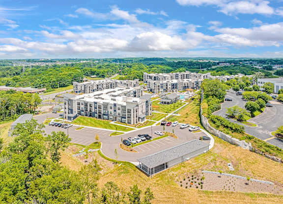 A large, modern building complex with a parking lot in front at The Percy Apartments, Nashville