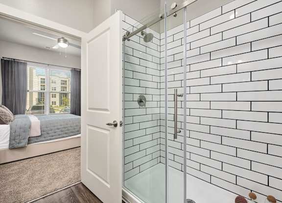 A white bathroom with a glass shower door at The Percy Apartments, Nashville