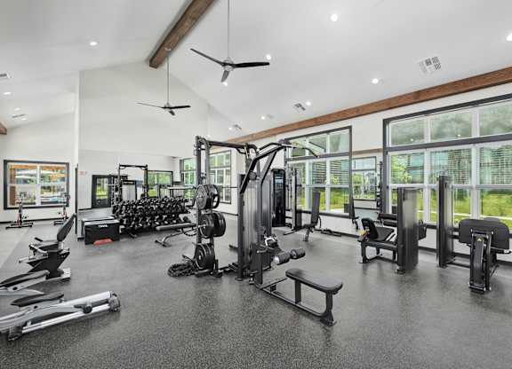 A spacious gym with a variety of equipment including treadmills, weights, and exercise machines at The Percy Apartments, Tennessee