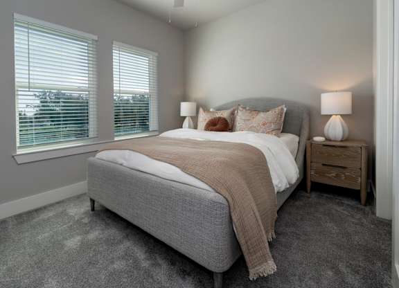 A bedroom with a large bed and two lamps at The Waverly at Winter Haven Apartments, Winter Haven, FL, 33884