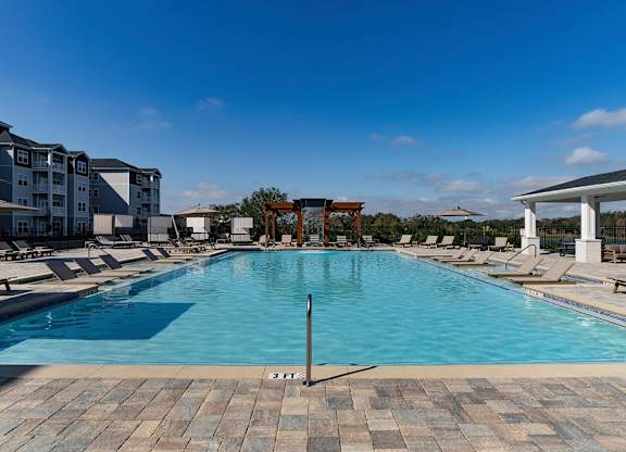 A large swimming pool with a depth marker in the middle at The Waverly at Winter Haven Apartments, Winter Haven
