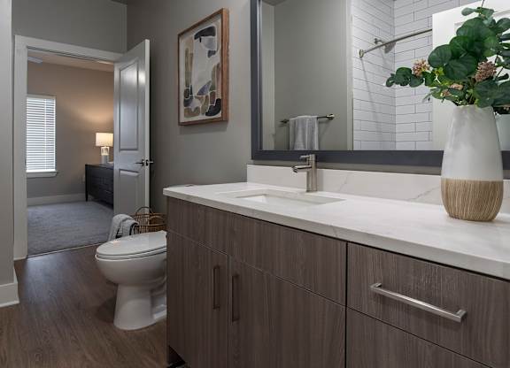 A bathroom with a toilet, sink, and mirror at The Waverly at Winter Haven Apartments, Winter Haven, FL