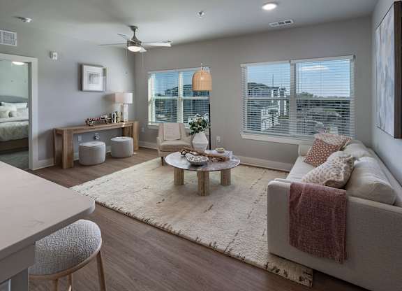 A well-lit, modern living room with a large couch and a coffee table at The Waverly at Winter Haven Apartments, Winter Haven, Florida