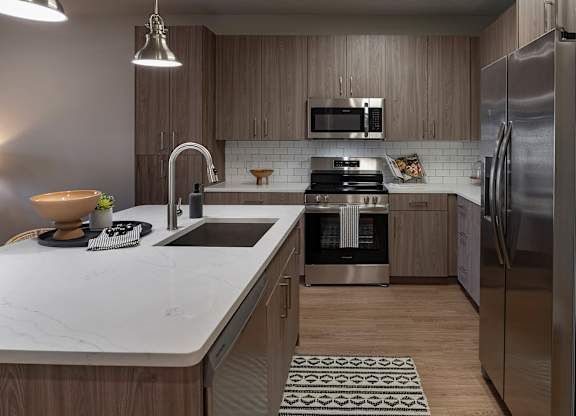 A modern kitchen with a marble countertop and stainless steel appliances at The Waverly at Winter Haven Apartments, Florida, 33884