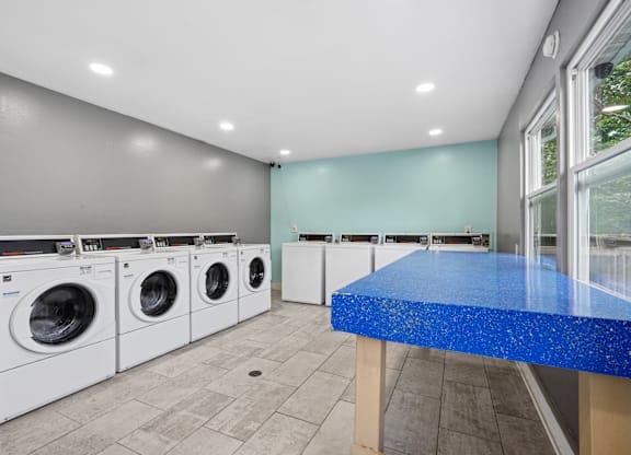 A laundry room with a blue counter and white washing machines.