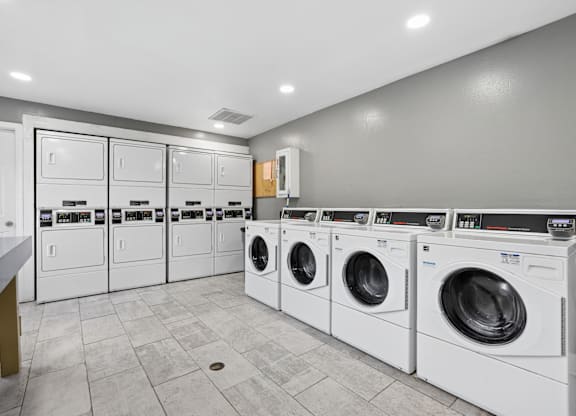 A row of white front load washing machines in a laundry room.