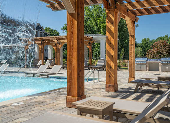 A poolside area with a waterfall and lounge chairs at The Ashton at East Park Apartments, Georgia