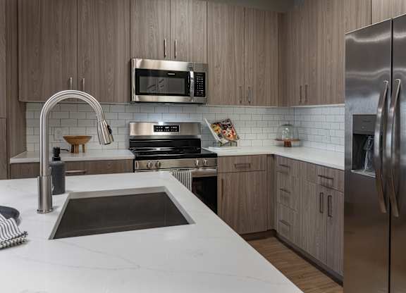 A modern kitchen with a stainless steel refrigerator and a white countertop at The Waverly at Winter Haven Apartments, Florida, 33884