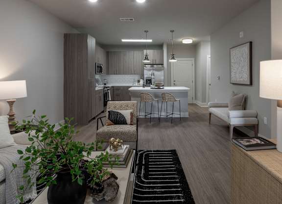 A well-lit, modern living room with a kitchen in the back at The Waverly at Winter Haven Apartments, Florida, 33884