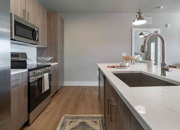 A modern kitchen with stainless steel appliances and wooden cabinets at The Waverly at Winter Haven Apartments, Florida, 33884