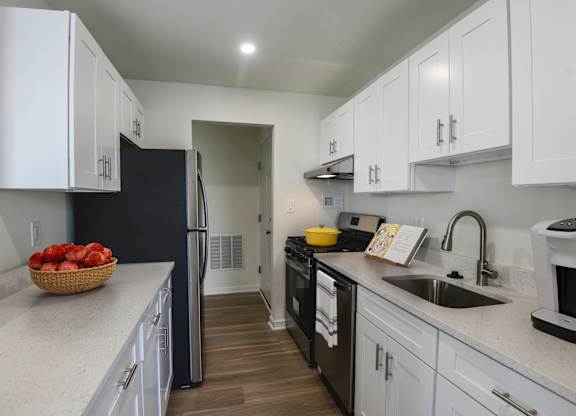 A kitchen with white cabinets and a black refrigerator.