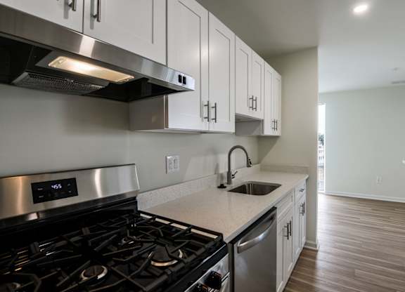 A modern kitchen with a stove, sink, and cabinets.