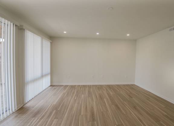 A room with wooden flooring and white walls.