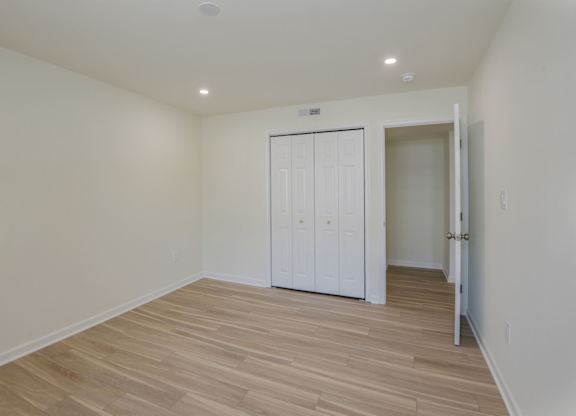 A room with a white door and wooden flooring.