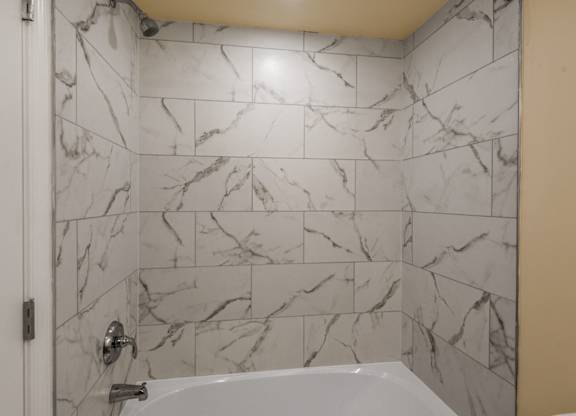 A white bathroom with a marble tile wall.
