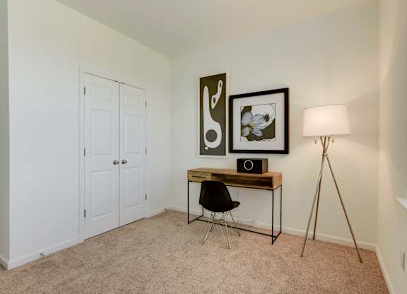 a bedroom with a desk with a lamp and a closet