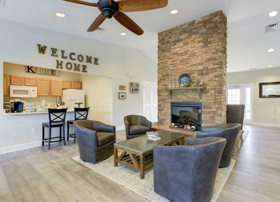 a living room with a stone fireplace and a table and chairs