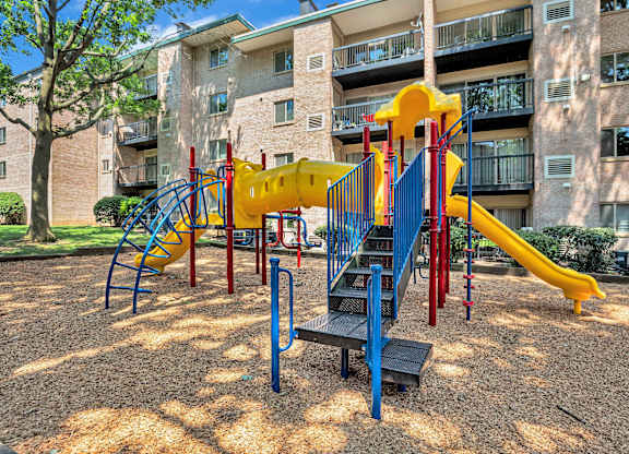 A playground with a yellow slide and a blue slide.