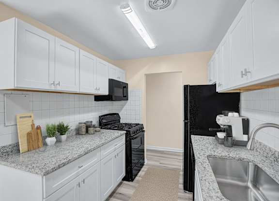 A kitchen with white cabinets and a black refrigerator.