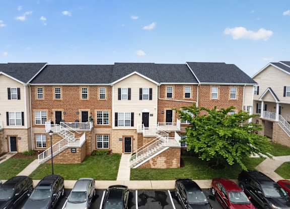 Apartment complex with a parking lot in front.