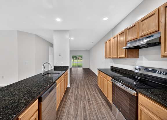 A modern kitchen with wooden cabinets and black countertops.